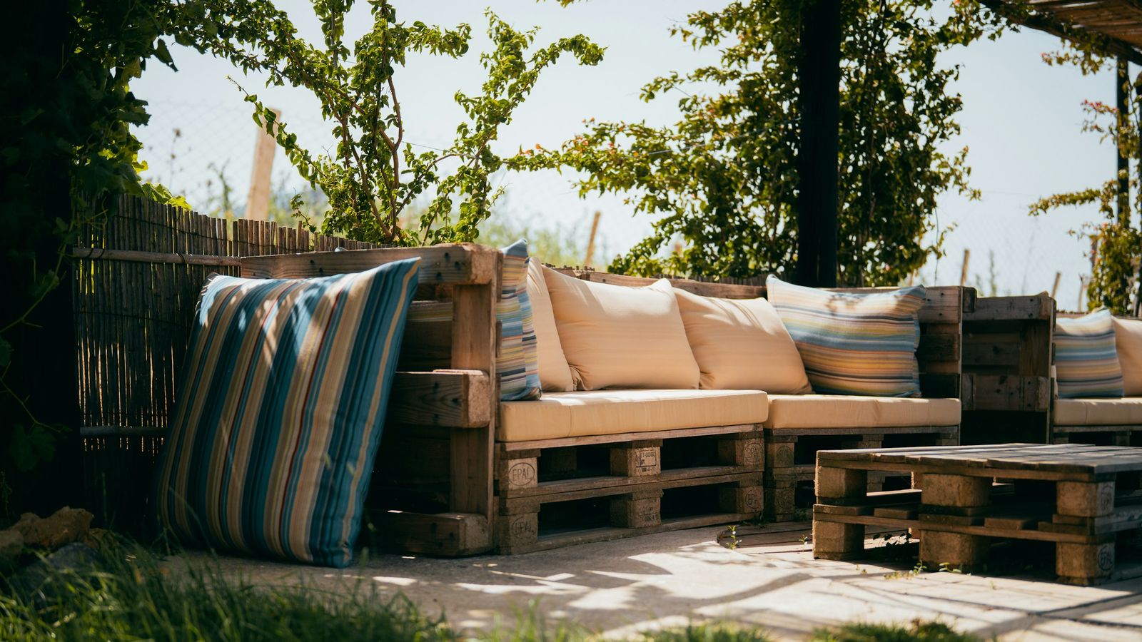 Garden seating made from wooden pallets with cream seat cushions and striped outdoor cushions